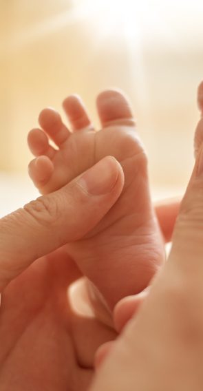 mum-making-baby-massage-mother-massaging-infant-bare-foot-preventive-massage-newborn-mommy-stroking-baby-s-feet-with-both-hands-light-background